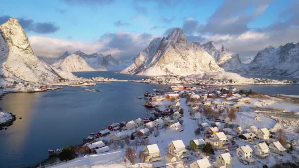 Αεροφωτογραφία του νησιού Lofoten της Νορβηγίας. Η χειμερινή περίοδος της ανατολής ψαροχώρι του Reine με snowscape κορυφή βουνό αντανακλούν στο νερό. Νορβηγία με κόκκινα σπίτια rorbu. Με χιόνι να πέφτει το χειμώνα. - Πλάνα, βίντεο
