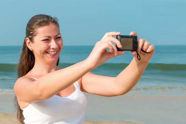 junge charmante Frau mit Kamera am Meer - Foto, Bild