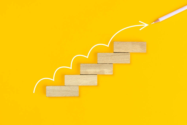 Ladder of success in business growth concept. Wooden block step stair, white arrow with white pencil up on yellow background - Zdjęcie, obraz
