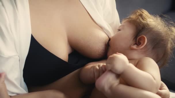 Zoom z azjatyckiego dziecka karmionego piersią przez matkę i bawiącego się nogami. Nakręcony aparatem hel RED w rozdzielczości 8K.   - Materiał filmowy, wideo