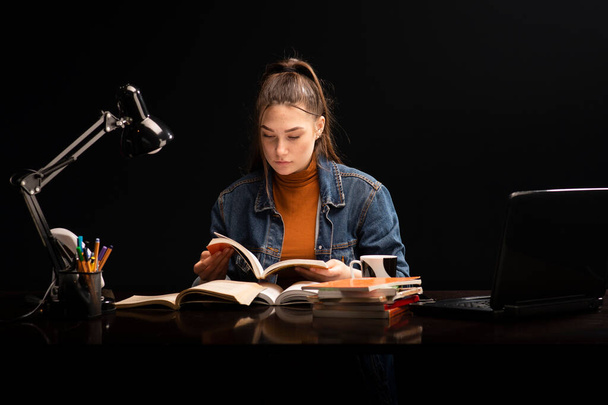 Жінка-студент, з книжками за столом. Дівчина сидить за столом і вчиться
 - Фото, зображення