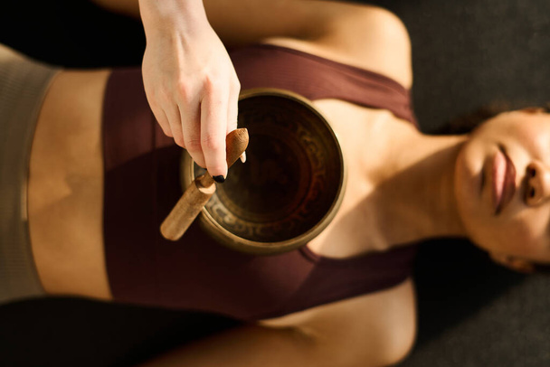 High angle view of young woman using singing bowl in yoga practice together with instructor - Photo, Image