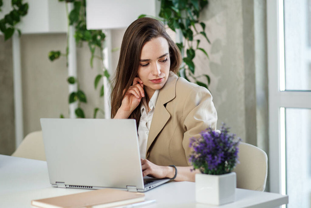 Женщина работает за ноутбуком в современном офисе. Данные по инвестициям в недвижимость, концепция финансовых и налоговых систем - Фото, изображение