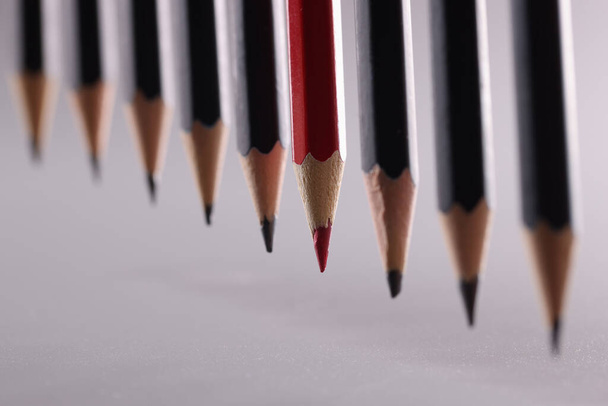 Lápiz rojo se destaca de la multitud de lápices negros idénticos. Liderazgo independencia profesional y estrategia para pensar de manera diferente - Foto, Imagen
