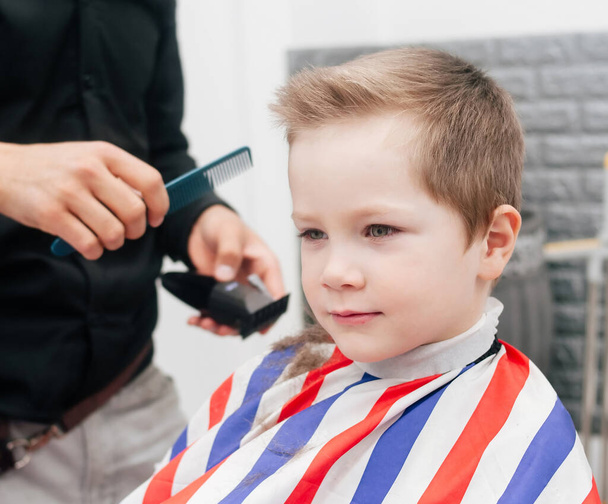 The boy, kid is getting a haircut in a barbershop, indoor. Lifestyle - Photo, Image
