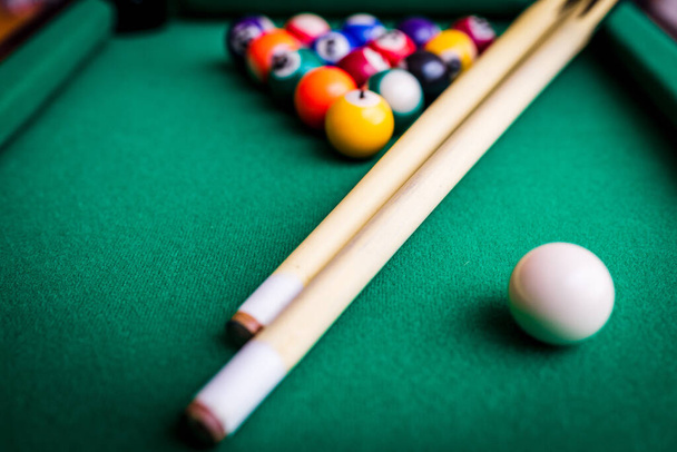 Billiard sport concept.Playing billiard.Billiard cues and pyramid of multicolored snooker pool balls on green billiard table. - Foto, afbeelding