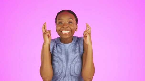 Black woman, fingers crossed and smile in studio, pink background and good luck face. Excited female, hands and wish for hope, winning giveaway and lottery prize with emoji sign, optimism and winner. - Metraje, vídeo