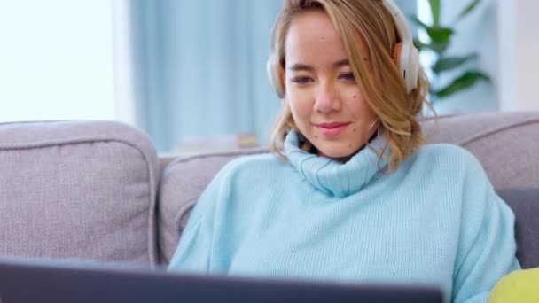 Laptop, fejhallgató és ázsiai nő a kanapén gépelés, online tanfolyam kutatás, e tanulás és zenehallgatás. Fiatal boldog diák vagy személy pihenni kanapén dolgozik a számítógép, audio és alkalmazás. - Felvétel, videó