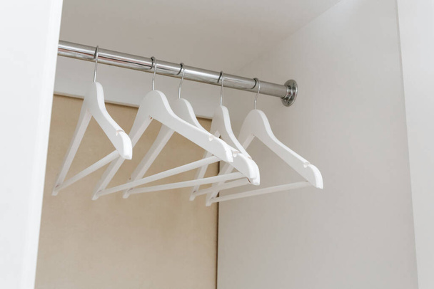 White empty wardrobe closet with hangers. Wooden white hangers on a rod. Store, sale, advertisement concept. - Fotoğraf, Görsel