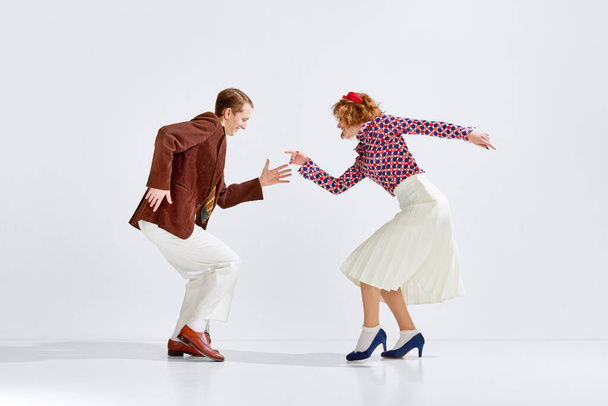 Old-school party. Young cheerful man and woman in stylish clothes dancing retro dance against grey studio background. Concept of art, retro style, hobby, party, fun, movements, 60s, 70s culture - Foto, Imagem