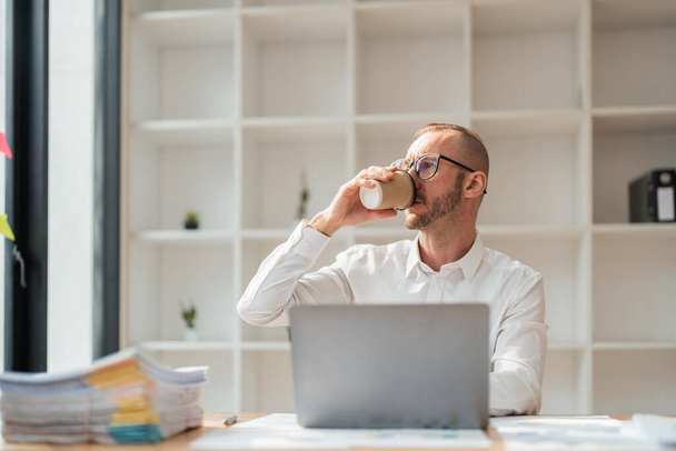businessperson working on laptop drinking coffee at office. - Photo, Image