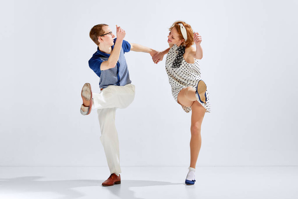 Beautiful young couple, man and woman in stylish retro costumes dancing dance against grey studio background. Concept of art, retro style, hobby, party, fun, movements, 60s, 70s culture - Фото, зображення