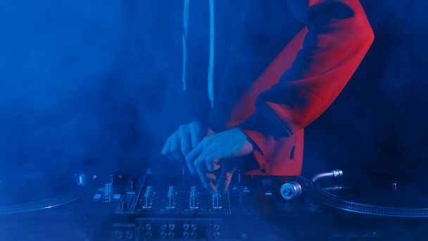 Hands of club DJ playing hip hop music set. Disc jockey using sound mixer to mix vinyl records - Photo, image