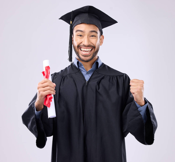 Graduation portrait of asian man, certificate and success isolated on studio background for university achievement. Fist pump of happy student, person or college graduate and diploma, award and goals. - Photo, Image