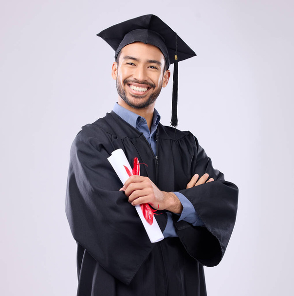 Graduation man, diploma and arms crossed in studio portrait with smile, success and pride for achievement. College graduate, asian student and certificate with goals, motivation and excited for award. - Photo, Image