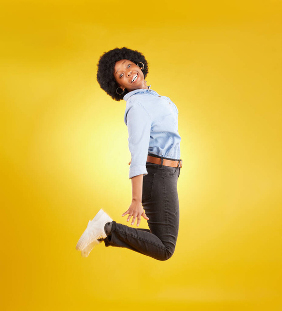 Happy, excited and portrait of black woman jump on yellow background with energy, happiness and smile in studio. Winner mockup, celebration and isolated girl jumping for freedom, winning and success. - Фото, изображение