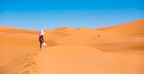 Young beautiful caucasian woman posing with white textile flying in the sahara desert in Morocco - Photo, image
