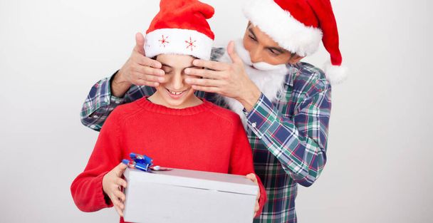 息子の目を覆う幸せな男はクリスマスに贈り物をする. - 写真・画像