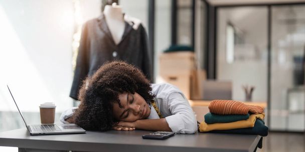 People tailor working in fashion design concept. Young adult asian designer woman tried and sleeping at workshop table. Background in business start up studio dressmaker... - 写真・画像