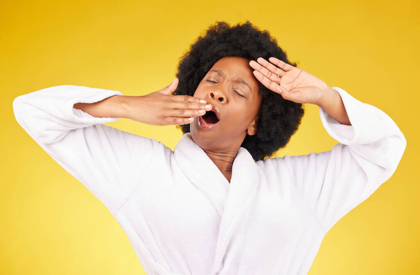 bâiller, matin et se réveiller avec une femme noire en studio sur un fond jaune portant un peignoir. Détendez-vous, fatigué ou reposez-vous avec une jeune femme épuisée bâillant et s'étirant après avoir dormi. - Photo, image