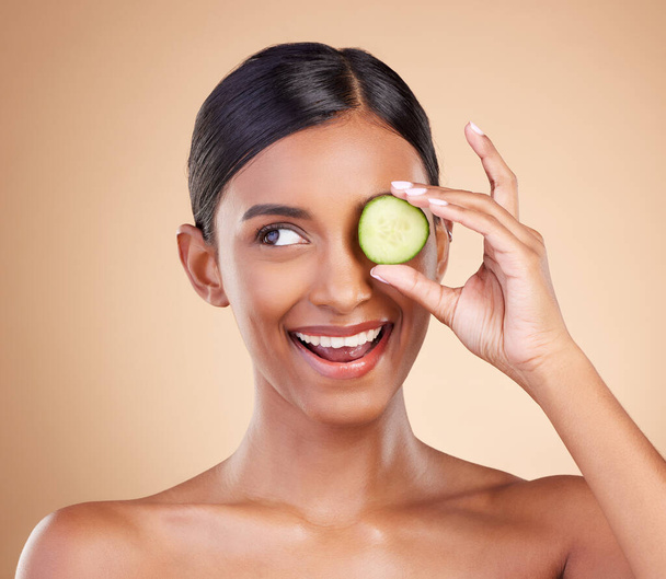 Smile, beauty or happy woman with cucumber for cleaning, detox and healthy facial treatment routine. Wellness, face or Indian girl with skincare nutrition or cosmetics isolated on studio background. - Fotoğraf, Görsel