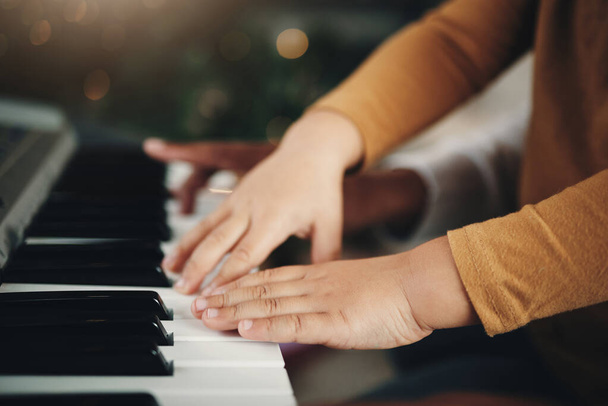 Apprendimento, pianoforte e mani di un bambino e di un genitore che suonano una canzone insieme. Educazione, musica e zoom di un bambino con un papà che insegna uno strumento durante una lezione musicale, aiuta e mostra a suonare. - Foto, immagini