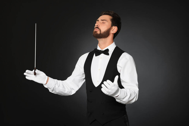 Professional conductor with baton on black background - Valokuva, kuva