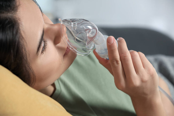 Sick young woman using nebulizer at home, closeup - Foto, afbeelding