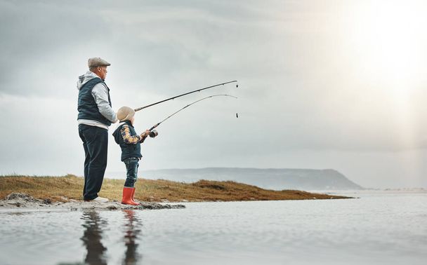 Göl, doğa ve büyükbaba macera, tatil ya da hafta sonu gezisinde bir çocukla balık tutuyor. Hobi, açık hava ve yaşlı bir adam çocuklara nehir kıyısında balık yakalamayı öğretiyor.. - Fotoğraf, Görsel