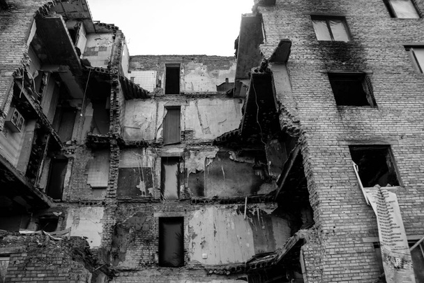 Facade of a building having received artillery fire. Most buildings in Gorenka are either destroyed or damaged beyond repair. The city was bombarded by Russian artillery in order to create an atmosphere of terror, these are war crimes - Fotoğraf, Görsel