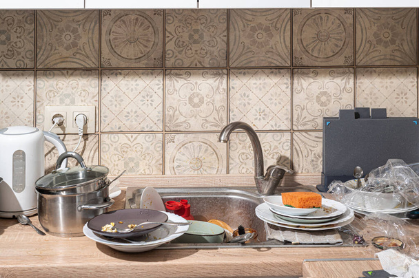 Cucina disordinata con piatti sporchi accatastati nel lavandino e sul bancone. Cucina moderna con facciate bianche in stile scandinavo - Foto, immagini