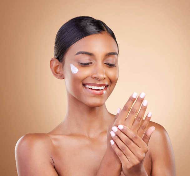 Hands, skincare or happy woman with cream product for beauty or young face isolated on studio background. Body cosmetics, smile or Indian girl with facial moisturizer or dermatology lotion for glow. - Foto, Imagem