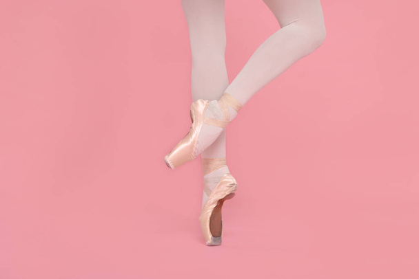 Young ballerina in pointe shoes practicing dance moves on pink background, closeup - Fotoğraf, Görsel