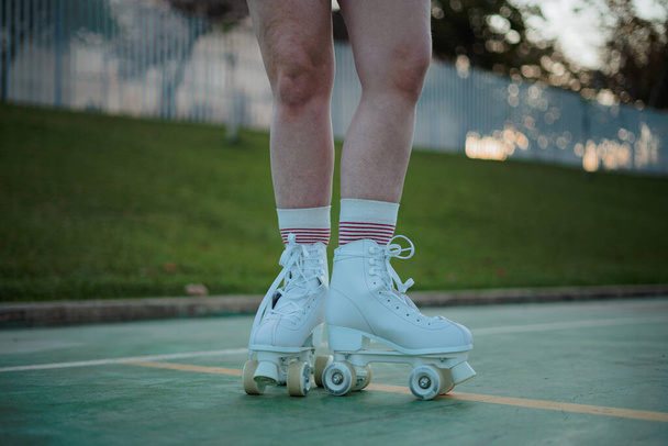 Cut out shot of legs of teenager with roller skates. She is at a field. - Photo, Image