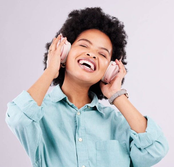 Music headphones, dance and happy black woman streaming song for studio fun, freedom and wellness. Dancing energy, audio podcast and person listening to radio, media sound or track on gray background. - Foto, immagini