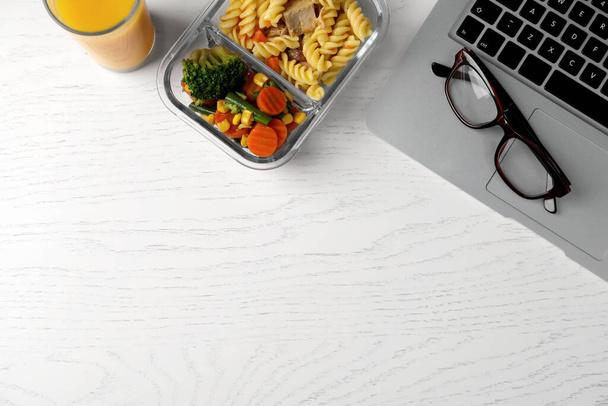 Container of tasty food, laptop and glasses on white wooden table, flat lay with space for text. Business lunch - Fotografie, Obrázek