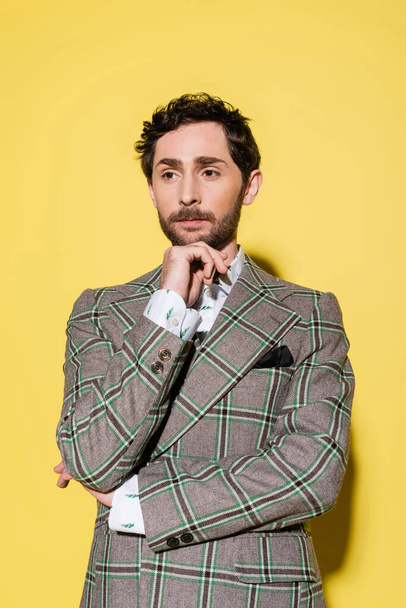 Portrait of stylish model in checkered jacket posing on yellow background  - Foto, immagini