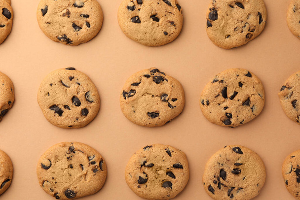 Many delicious chocolate chip cookies on beige background, flat lay - Foto, afbeelding