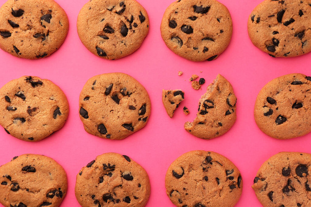 Many delicious chocolate chip cookies on pink background, flat lay - Фото, изображение