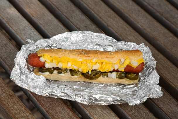 Fresh tasty hot dog with sauce on wooden surface - Foto, afbeelding