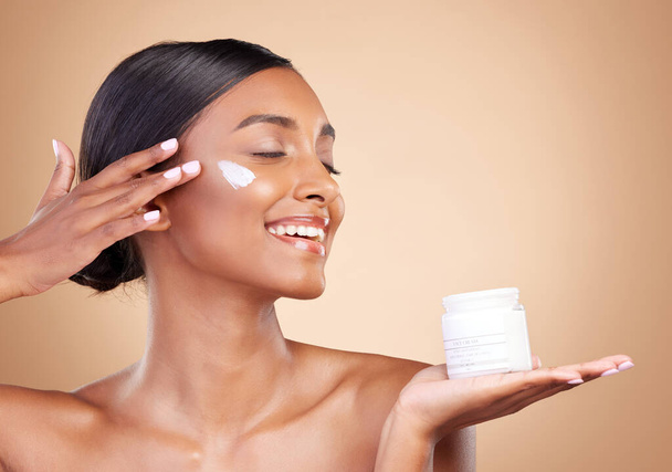 Smile, skincare or happy woman with cream product for beauty or young face isolated on studio background. Body cosmetics, youth or Indian girl with facial moisturizer or dermatology lotion for glow. - Φωτογραφία, εικόνα