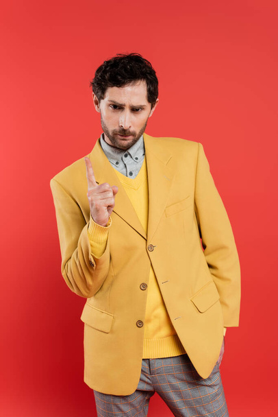 displeased man in yellow jacket pointing with finger while warning isolated on coral red  - Foto, Imagem