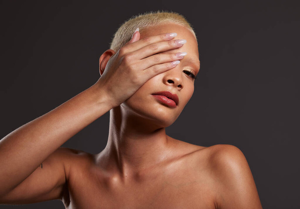 Posing, skincare and portrait of a woman with makeup isolated on a black background. Beauty, grooming and African model with hand on face, covering eye and showing a glow on skin on a backdrop. - Fotoğraf, Görsel