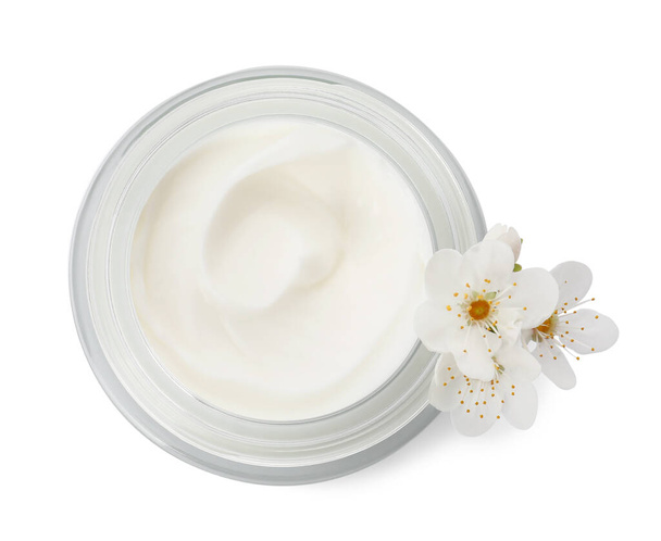 Glass jar of face cream and flowers on white background, top view - Foto, Imagen