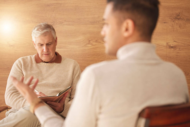 Psychologist, counseling or man consulting in therapy, mental healthcare or support in consultation. Back view of patient talking to writing or listening senior therapist for medical help or advice. - Photo, Image