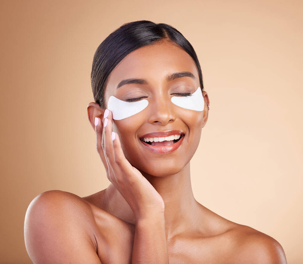 Face, skincare or happy woman with eye patch for beauty or wellness isolated on studio background. Cosmetics or girl model with facial collagen pads or dermatology product for anti aging or hydration. - Photo, Image