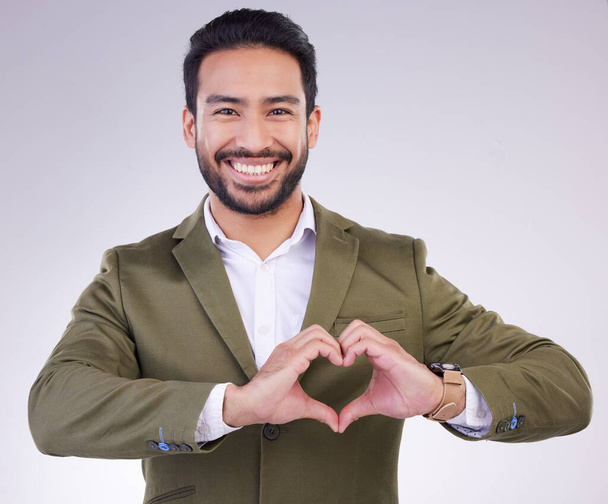 Hands, heart shape and business man portrait in studio for support, love and charity on a gray background. Asian entrepreneur person with hand emoji or icon for care, motivation and kindness smile. - Photo, Image