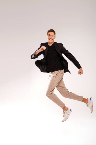 Crazy young man in casual clothes jumping over studio background with big smile on his face. People success concept. Copy space.  - Foto, Imagen