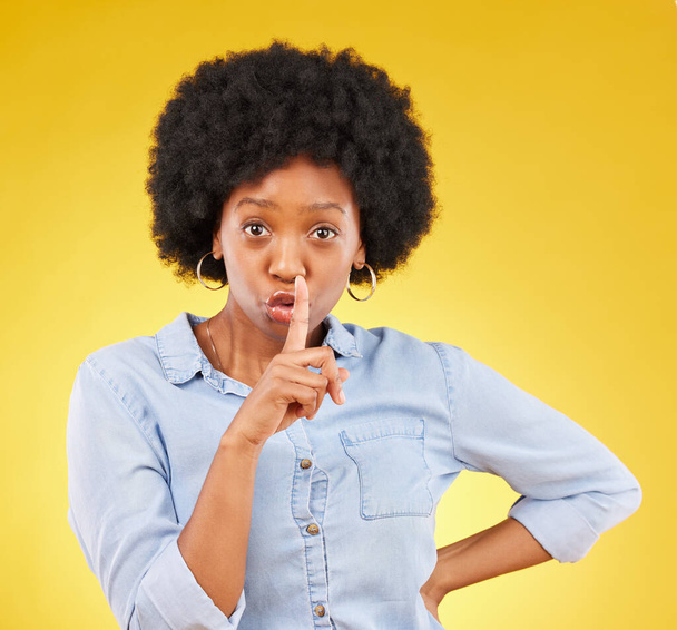 Privacy, secret and finger on lips of black woman in studio for mystery, gossip and announcement. Noise, news and whisper with female and shush gesture on yellow background for rumor, drama or silent. - Photo, Image