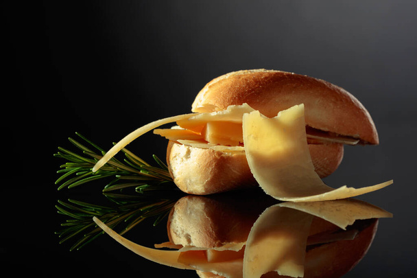 Sandwich with Parmesan cheese and rosemary on a black reflective background. - Foto, Imagem